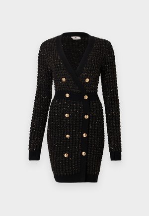 Melna adīta kardigāna ar teksturētu apdari, V-veida kakla izgriezumu, garām piedurknēm un dubultās pogas ar zelta krāsu. Ribotas piedurknes un josta.