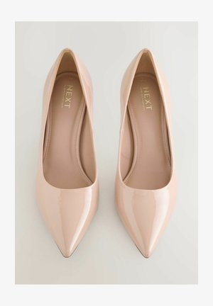 Spitze Pumps aus nudefarbenem Lackleder mit glänzendem Finish, die eine glatte Textur und ein minimalistisches Design aufweisen. Markenlabel innen sichtbar.