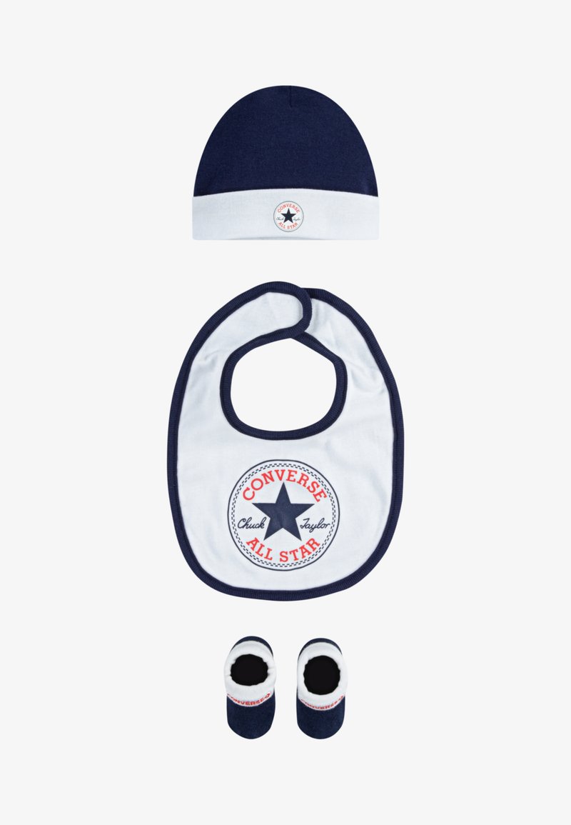 Bonnet en tricot marine, bavoir blanc avec logo rouge et bleu, et chaussons marins avec accents blancs. Matériau en coton, formes rondes, accessoires pour tout-petits.