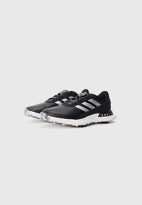 Black athletic shoes with a smooth synthetic upper, three silver stripes, a white midsole, and a textured black outsole for traction.