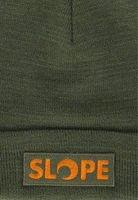 Olivgrön stickad mössa med vikt kant. Har en orange "SLOPE" logotyp patch. Materialet verkar mjukt och texturerat.