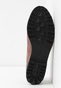Semelle d'une chaussure en daim marron avec une bande de roulement en caoutchouc noir présentant des rainures profondes et des motifs en forme de croix, de la marque "Gabor".