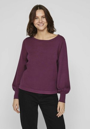 Pull en tricot violet avec un col large, des manches ballon longues et une coupe décontractée. Associé à un pantalon noir, présenté sur un fond neutre.