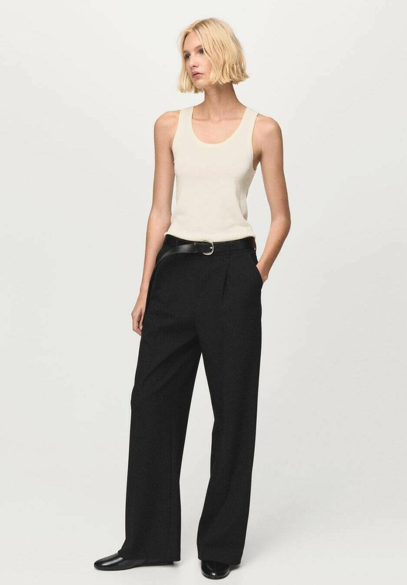 Top de tirantes color beige claro con escote redondeado, combinado con pantalones negros de pierna ancha y cintura alta, y un cinturón negro con hebilla redonda.