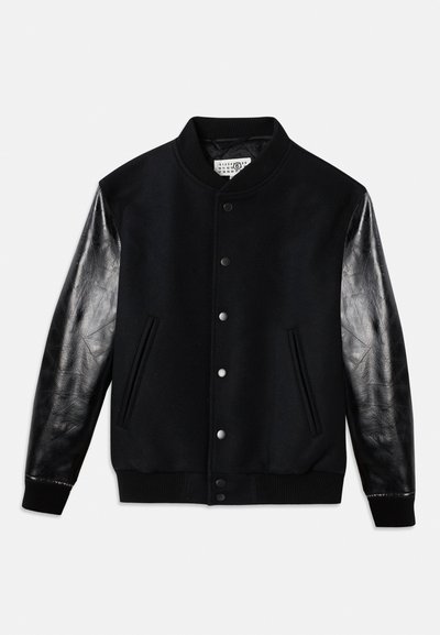 Jachetă varsity neagră cu corp din lână și mâneci din piele neagră lucioasă. Are nasturi tip snap și buzunare laterale, cu manșete și tiv din material ofilit.