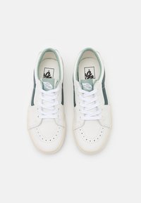 Sneaker bianche con dettagli verdi, materiali in pelle e tessuto, punta rotonda, punteggiatura sulla zona delle dita, lacci piatti e etichetta con marchio sulla linguetta.