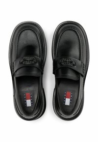 Schwarze Leder-Schlüpfschuhe mit runder Form, ausgestattet mit einem breiten Riemen und silbernem Beschlag. Das Innenfutter hat ein Markenschild mit rot, weiß und blauen Akzenten.