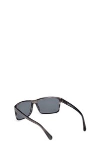 Occhiali da sole con lenti grigie, forma rettangolare e una montatura in plastica a strisce nere e grigie, con un logo discreto sulla tempia.