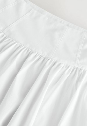 Valkoinen hame, jossa on kerätty alaosa, sujuva vuorattu vyötärö ja pehmeä, kevyt kangas. Muotoilussa on hienovaraisia ompelutietoja.