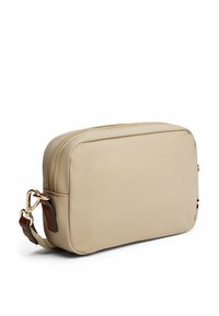 Borsa in tessuto beige con superficie liscia, forma rettangolare, chiusura con zip e dettagli in pelle marrone. Presenta un piccolo logo in rosso, bianco e blu.