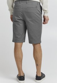 Shorts de algodón gris con corte recto, bolsillos laterales y dos bolsillos traseros, con textura de tela suave y detalles de costura limpios.