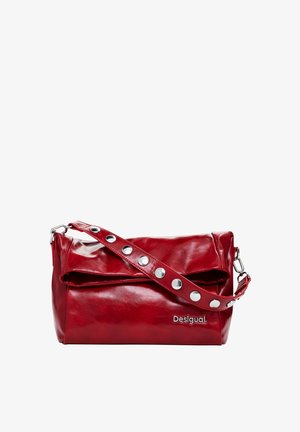 Bolso de hombro de piel roja con tachuelas redondas plateadas en la correa y logo metálico de la marca en el frente, forma rectangular con parte superior doblada.