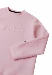 Różowa bluza z długim rękawem i okrągłym dekoltem, z wytłoczonym logo "reima" na piersi, prezentowana na białym tle.