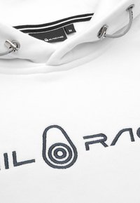 Sudadera blanca con capucha ajustable, cuello interior a rayas en blanco y negro, y logo bordado en gris oscuro que dice "RACING" con un diseño circular.