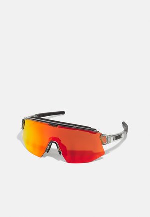 Czerwone okulary przeciwsłoneczne o eleganckim designie, z dużą, zakrzywioną soczewką, czarnymi akcentami i przezroczystą plastikową ramką. Zawierają błyszczące metaliczne detale.