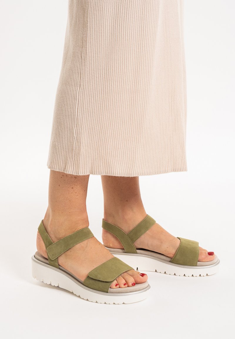 Green suede sandals with wide straps and a white, textured platform sole. Designed with open toes and an adjustable ankle strap.