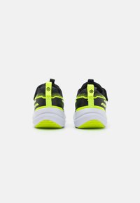 Des chaussures de sport noires et jaune néon avec une tige en mesh, une semelle amortissante et un logo cousu à l'arrière. Elles présentent une languette pour un enfilage facile.