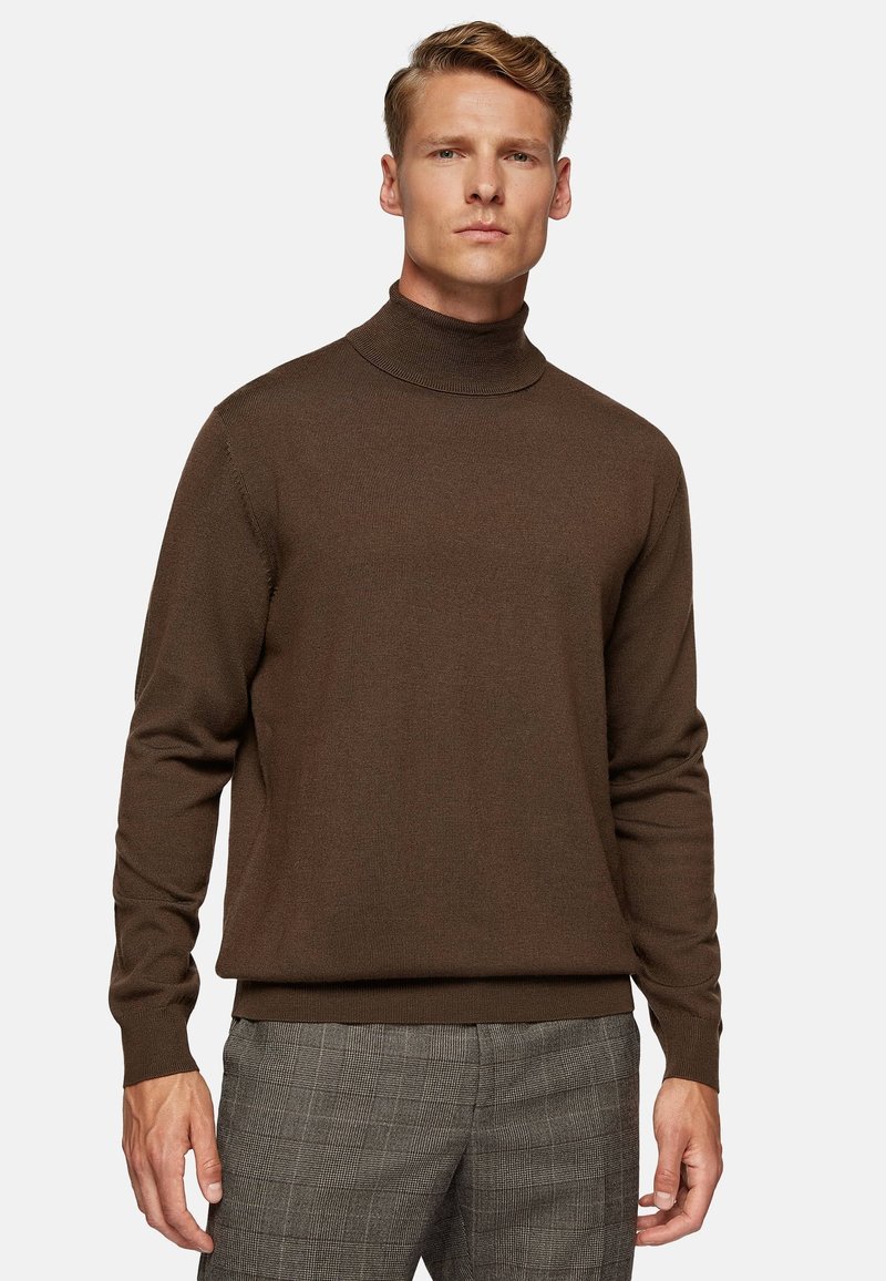 Brown turtleneck sweater in a ribbed texture with long sleeves and a fitted silhouette, paired with gray checked trousers.