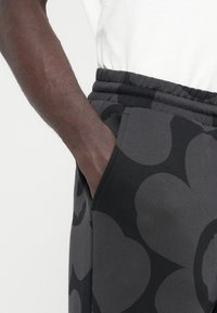 Γκρι φόρμες με μεγάλο μαύρο αφηρημένο σχέδιο, κατασκευασμένες από μαλακό ύφασμα, με ελαστική μέση και πλαϊνές τσέπες.