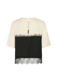 Blouse crème et noire à manches courtes avec un bord en dentelle en bas et une petite ouverture en forme de goutte dans le dos.