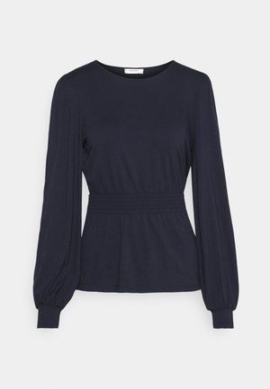 Marineblaue Langarmbluse mit geraffter Taille, rundem Ausschnitt und elastischen Bündchen vor einfarbigem Hintergrund.