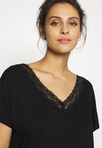 Black V-neck top featuring short sleeves and a lace trim along the neckline, made from soft fabric with a smooth texture.