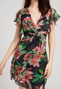 Vestido floral con mangas cortas en volantes, presenta un fondo negro con flores rosas y verdes vibrantes, cintura anudada y escote en V.