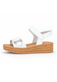 White wedge sandals with a cork sole, featuring an adjustable ankle strap and a rectangular buckle detail on the upper strap.