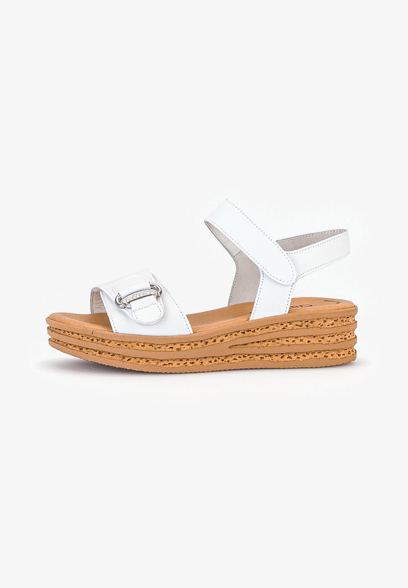 White wedge sandals with a cork sole, featuring an adjustable ankle strap and a rectangular buckle detail on the upper strap.