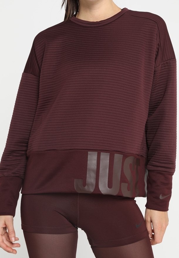 Burgundowa bluzka sportowa z fakturowanym ryflem, z napisem "JUST" w ciemniejszym odcieniu z przodu, w zestawie z ciemnymi szortami.