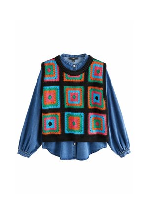 Haakveste, millel on värvilised ruuduline mustrid punases, sinises, rohelises ja roosas mustal taustal, kihtidega denimist särgi peal, millel on paisutatud varrukad.