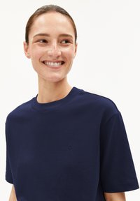 Marineblauwe katoenen t-shirt met korte mouwen, ronde hals en een klein geborduurd logo op de borst. Rechte textuur en casual pasvorm.