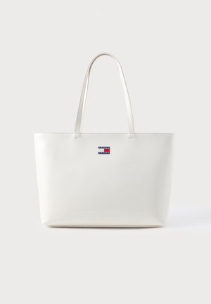 Biała torba tote z dwiema długimi rączkami, gładka faktura, minimalistyczny design, z małym, wielokolorowym logo z przodu.