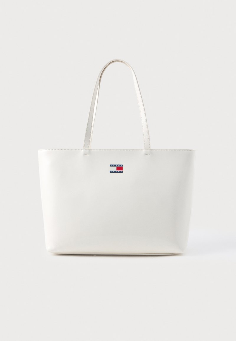 Geantă albă tip tote cu două mânere lungi, textură netedă, design minimalist, având un mic logo multicolor pe partea din față.