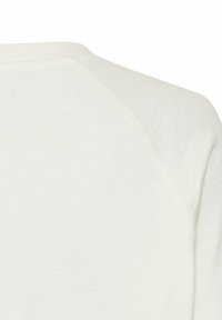 Witte lichte kledingstuk van een zachte, textuurrijke stof. Beschikt over een ronde halslijn en raglanmouwen, met een eenvoudig, minimalistisch design.