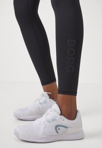 Leggings pretas com o logótipo "BORG" em cinza, combinadas com sapatilhas brancas desportivas com detalhes em azul claro e painéis texturizados.