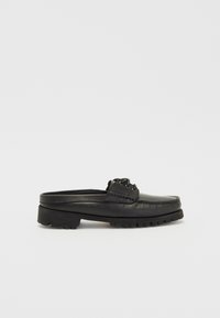 Chaussure noire en cuir à enfiler avec un bout arrondi, des coutures décoratives et une semelle en caoutchouc épaisse. Comprend deux œillets pour les lacets.