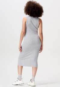 Robe midi grise sans manches au design ajusté, texture côtelée et finition lisse. Portée avec des baskets blanches et des chaussettes à motifs.