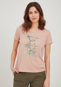 Camiseta de manga corta color rosa claro, hecha de una tela suave, con un estampado botánico que incluye texto en francés en verde y negro. Corte sencillo y relajado.
