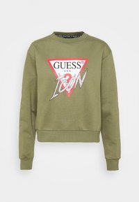 Sweatshirt vert olive avec un col rond, arborant un logo triangulaire rouge avec "GUESS" et "ICON" en embellissements argentés.