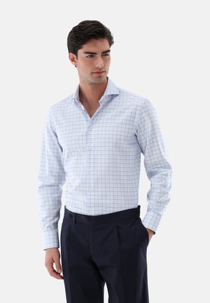 Camicetta a quadri blu chiaro con colletto all'americana. Presenta bottoni bianchi e maniche lunghe, abbinata a pantaloni blu scuro.