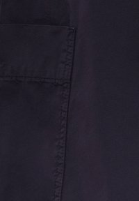 Tissu bleu marine foncé avec une texture lisse, comprenant une couture latérale visible et un détail de poche. Les bords cousus sont nets et réguliers.