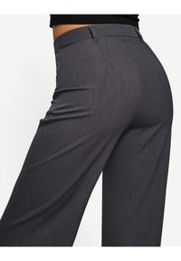 High-waisted gray trousers with a smooth texture, featuring a tailored fit and subtle vertical stripe pattern, detailed with front pockets.
