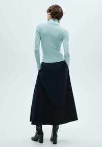 Žametna svetlo modra turtleneck bluzica, pritrjena na dolgo črno krilo. Obleka vključuje oprijet zgornji del z dolgimi rokavi in črnimi čevlji do gležnjev.