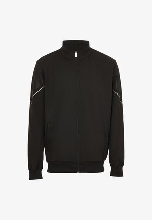 Zwarte zip-up jas van zachte stof. Voorzien van een opstaande kraag, zijzakken en reflecterende accenten op de schouders. Gemoedelijke textuur.