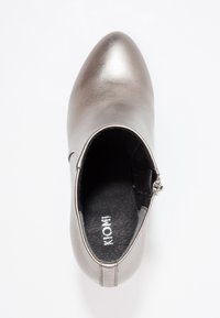 Botín metálico plateado hasta el tobillo con punta afilada, textura suave, cremallera lateral para el cierre y un forro interior negro.