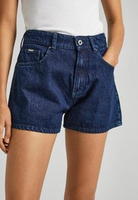 Denim shorts in dark blue, featuring a high waist, front pockets, and a straight cut with subtle fading and stitching details.