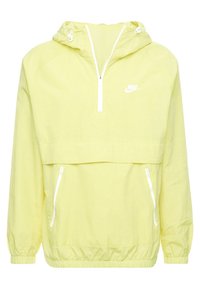 Ljusgul Nike vindjacka med huva, halvmångsgång framtill, elastiska ärmar, två vita dragkedjefickor på sidorna och justerbar dragsko.