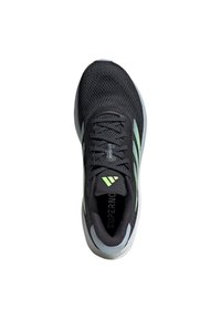 Black athletic shoe with mesh upper, lime green accents, and rubber sole. Features lacing system and "Supernova" branding on the insole.
