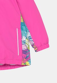 Helle pinke Jacke mit einem gemusterten Futter, das türkisfarbene, gelbe und pinke Wellen zeigt; elastische Bündchen; mit weißen Reißverschlussdetails.